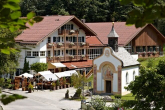 Alpine house with balconies, chapel and café terrace in a green landscape