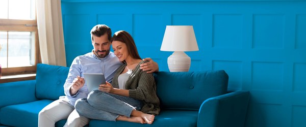 Couple sitting on a blue sofa looking at a tablet, from the A2A Energia website