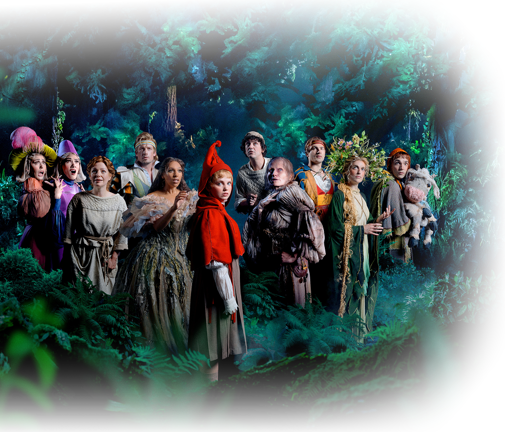 The company of Into the Woods on stage in a lush forest setting at the Noël Coward Theatre