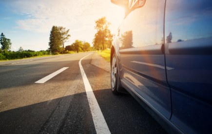 Car on a sunlit road at sunrise