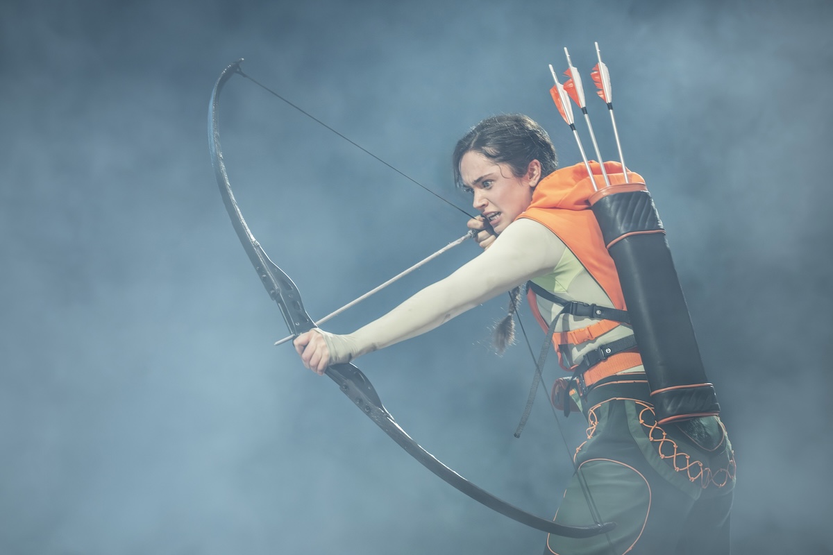 Katniss Everdeen draws her bow in The Hunger Games: On Stage