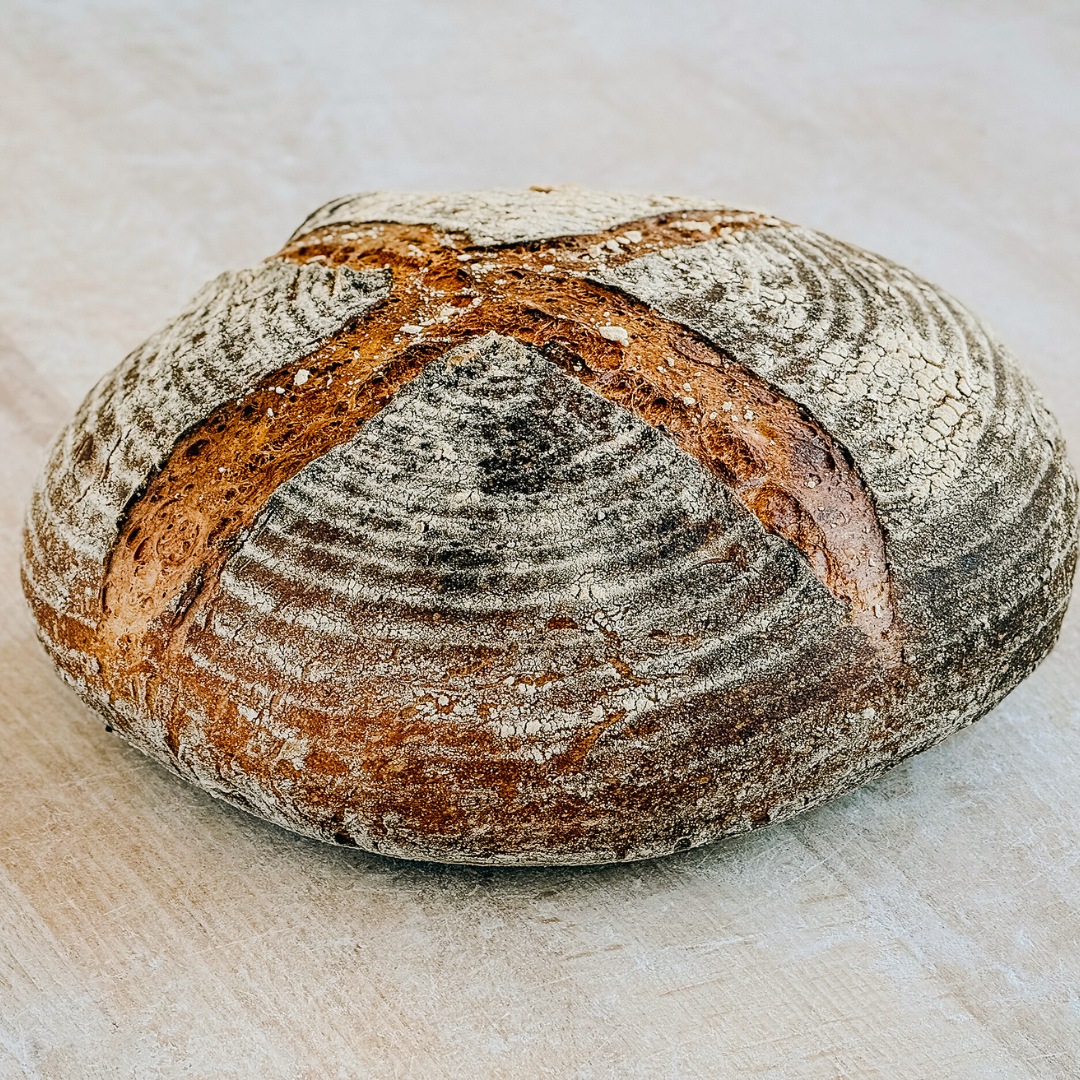 Round rustic sourdough loaf with a dark, crackled crust