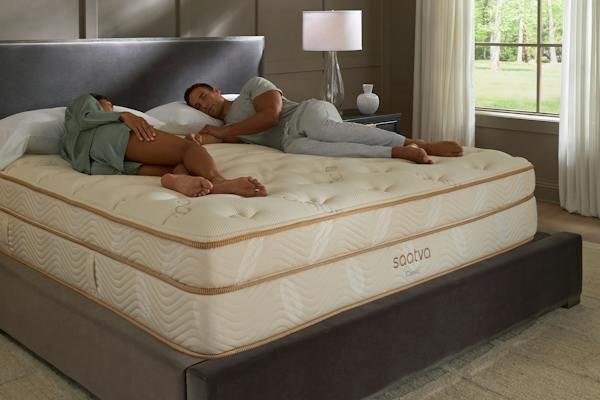 Couple relaxing on a Saatva Classic mattress in a bright bedroom