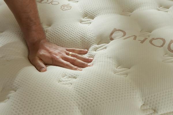 Hand pressing into the quilted top of a Saatva Classic mattress