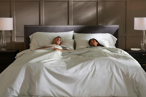 Person sleeping under white bedding on a Saatva Classic mattress